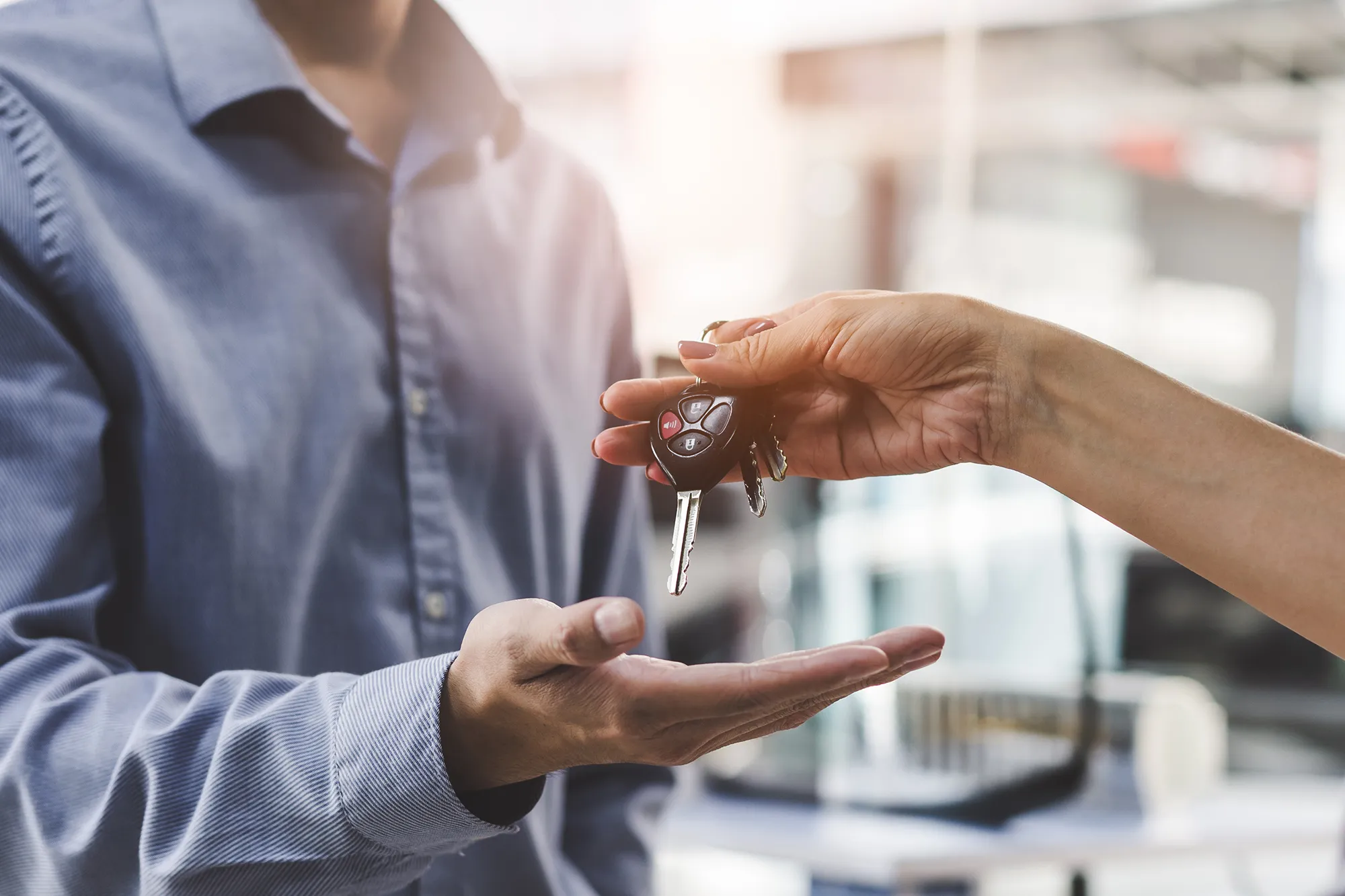 Image of a person giving car keys to another person, to illustrate returning a leased vehicle